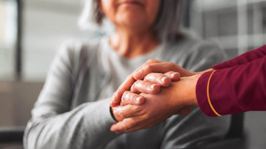 A support worker holding a client’s hand