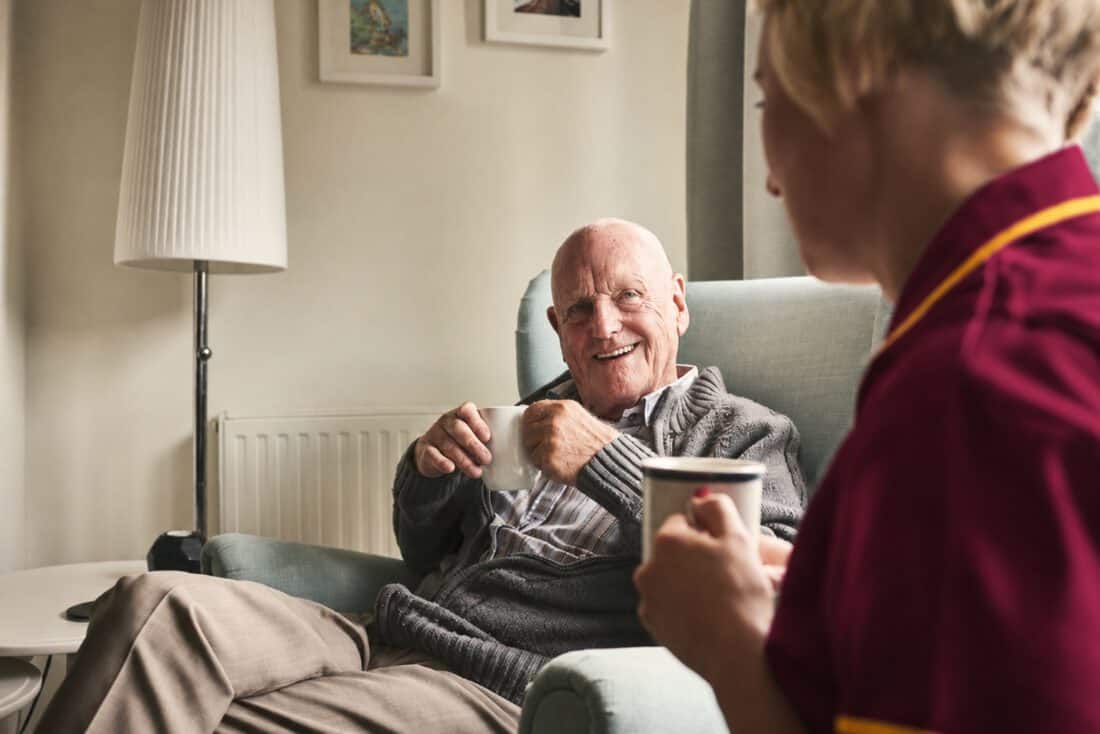 A support worker sharing a cup of tea with an older man